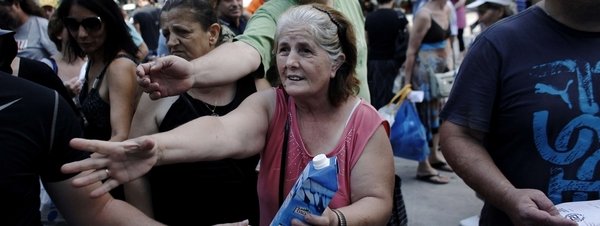 Una mujer pide comida a miembros de Amanecer Dorado en Atenas.