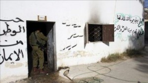 Un soldado israelí revisa los daños registrados en una escuela en la que han hecho pintadas. 