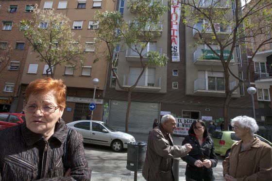 Ana, a la izquierda, propietaria de dos pisos en el edificio 'ocupado' en Nou Barris, al fondo.