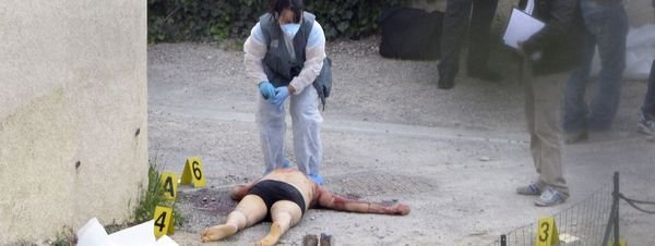 Agentes de policía buscan pruebas en la secena del crimen donde una persona yace muerta tras un tiroteo en el que han fallecido tres en Istres cerca de Marsella (Francia)