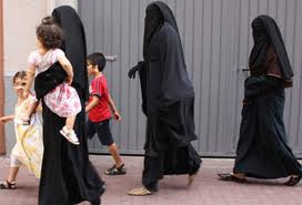 Tres catalanas pasean por una calle de Vilanova acompañadas de sus hijos.