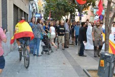 En la imagen, un miembro del PEC cubierto por la bandera de España pasa a bordo de su bicicleta junto a una concentración de separatistas el pasado día 11.