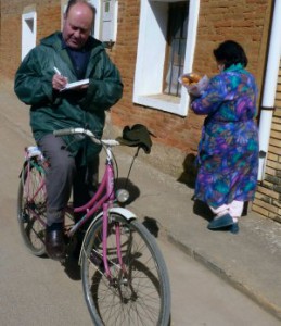 El Padre Jesús Calvo recorre en bicicleta las calles de Villamuñio (León) para tomar nota de las necesidades de sus parroquianos