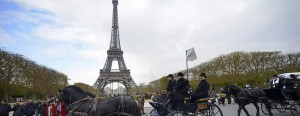 Un coche de caballos cruza por delante de la torre Eiffel de París. 