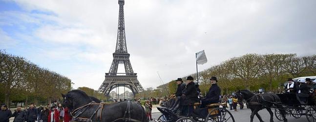 Un coche de caballos cruza por delante de la torre Eiffel de París.