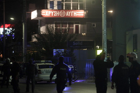 Policías delante del local del partido Amanecer Dorado, donde dos hombres han sido asesinados a balazos este viernes