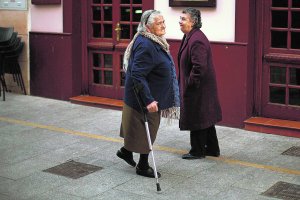 Dos mujeres de edad avanzada se cruzan en una acera.