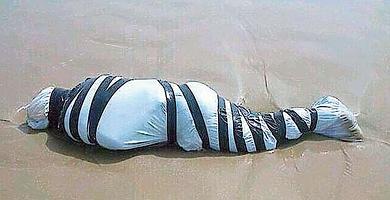 El cuerpo sin vida arrastrado por el mar, ayer, envuelto en plástico y rodeado de cinta negra.