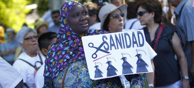 Una mujer inmigrante sostiene una pancarta contra los recortes en la novena 'marea blanca' por la sanidad pública en Madrid.
