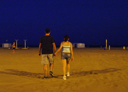 Una pareja se interna en la playa de la Malvarrosa.