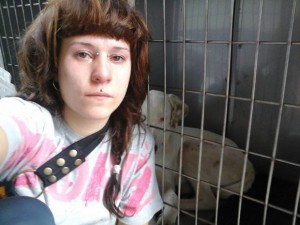Imagen de la joven junto a la jaula en la que se mantiene encerrada a su perra