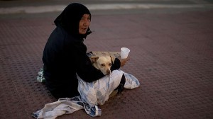 Mujer, junto a su perro, pide limosna en una calle de Málaga