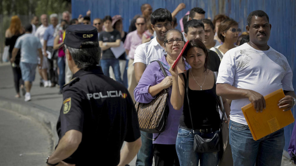 Inmigrantes hacen cola a la entrada de la Brigada Provincial de Extranjería y Fronteras del CIE de Aluche en Madrid