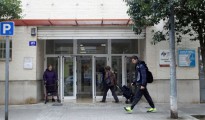 Dos pacientes en la entrada de un centro de salud de Valencia mientras un viandante pasa por la puerta.