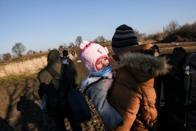 Un niño llora mientras inmigrantes y refugiados caminan cerca de la localidad serbia de Miratovac, tras cruzar desde Macedonia, el 30 de enero de 2016