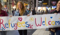 Tres jóvenes suecas portan una pancarta dando la bienvenida a los refugiados.