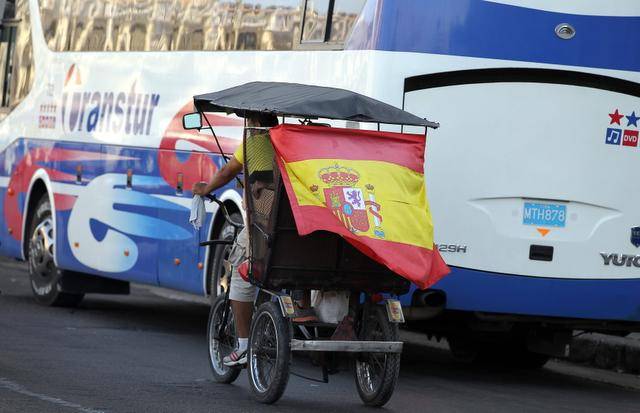 Un bicitaxi circula con una bandera de España en Cuba