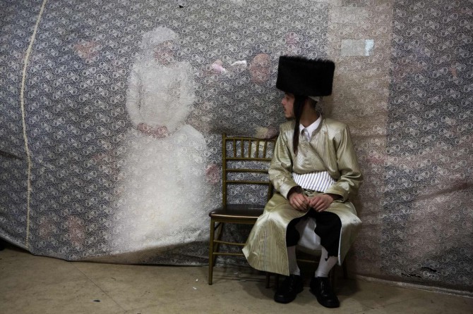 Una novia judía, Rivka Hannah, mira a su futuro marido, Aharon Krois, desde detrás de una cortina en el baile ritual Mitzvah Tans durante su boda, en un barrio ultraortodoxo de Jerusalén.