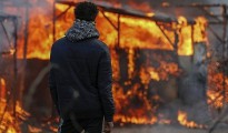Un hombre observa un refugio en llamas durante el inicio del desmantelamiento del campamento de Calais