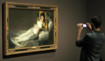 Un joven fotografía "La maja vestida" de Goya, expuesta en CaixaFórum Barcelona.