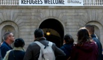 Un cartel anuncia "Bienvenidos Refugiados" desde la fachada del ayuntamiento de Barcelona, el 18 de marzo de 2016, días después de que la alcaldesa Ada Colau firmara un acuerdo de cooperación con sus homólogos de Lampedusa y Lesbos