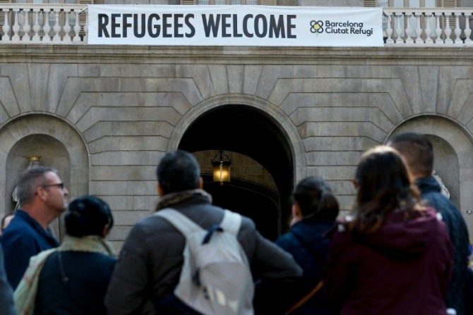 Un cartel anuncia "Bienvenidos Refugiados" desde la fachada del ayuntamiento de Barcelona, el 18 de marzo de 2016, días después de que la alcaldesa Ada Colau firmara un acuerdo de cooperación con sus homólogos de Lampedusa y Lesbos
