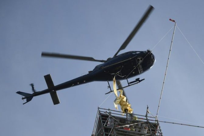 Un helicóptero traslada la estatua del arcángel del Monte Saint Michel a lo alto de la abadía.