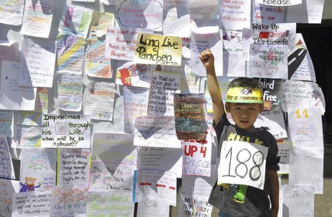 Un niño posa delante de una pared cubierta con mensajes de activistas tibetanos con motivo de la conmemoración, el pasado 17 de mayo, del 21 aniversario del secuestro de un niño tibetano de siete años , considerado como la reencarnación del Panchen Lama, en Dharamshala, India. 