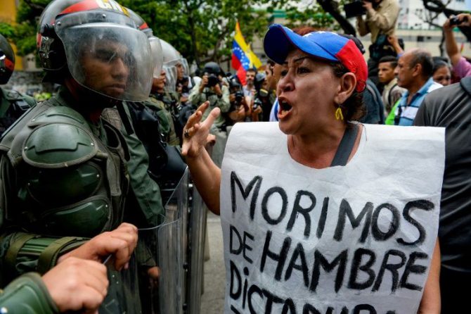 Una mujer exhibe un cartel que seña "Morimos de hambre" durante una protesta contra el estado de emergencia decretado por el presidente Nicolás Maduro, el 18 de mayo de 2016 en Caracas