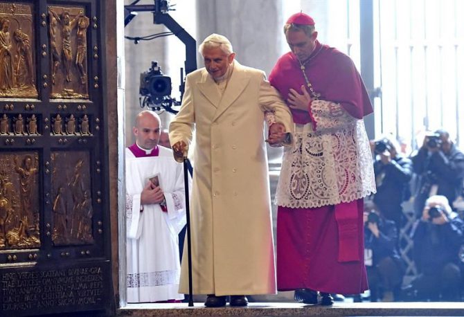 El papa emérito Benedicto XVI (i) cruza la Puerta Santa con la ayuda del cardenal alemán Georg Gaenswein durante la inauguración del Jubileo Extraordinario de la Misericordia, en el Vaticano, el 8 de diciembre de 2015.
