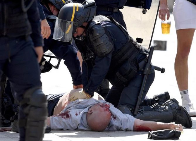 Un policía atiende a un aficionado tras una pelea por las calles de Marsella. 