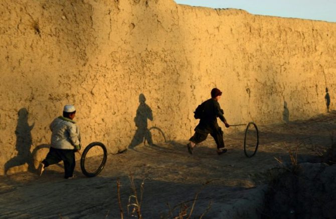 Un niño afgano juega con un neumático.