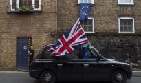 Un taxista londinense ondea una bandera británica mientras circula por una calle donde una bandera europea ondea en una ventana en Londres (Reino Unido) hoy, 24 de junio de 2016.