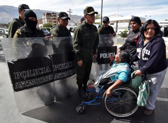 Policías Bolivianos desalojan a una docena de personas con discapacidad, en sillas de ruedas y con muletas luego de que protestaran frente a las puertas de la clínica donde operaron de una rodilla al presidente boliviano, Evo Morales, y que estuvo custodiada por decenas de policías.