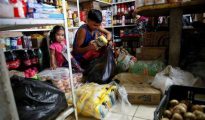 En la imagen, un niño mete paquetes de harina de maíz colombiana en una bolsa de plástico, en un mercado en La Fria, Venezuela.