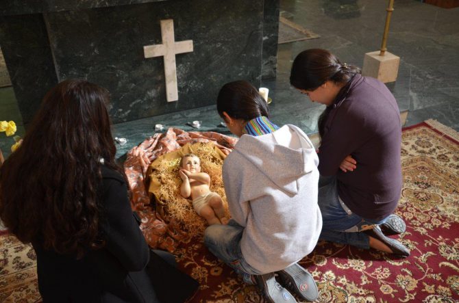 Tres jóvenes refugiadas rezan ante un Pesebre la pasada Navidad.