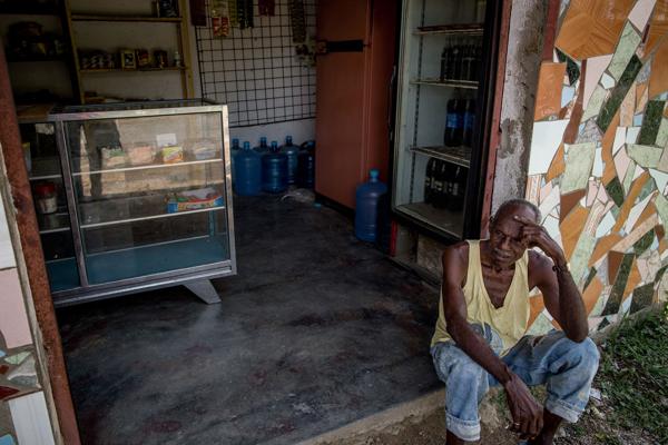 Un hombre descansa en la entrada de su tienda en Barlovento. Desde enero no le reparten comida. Apenas subsiste (Washington Post)