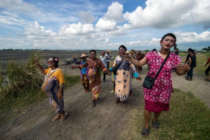 Sobrevivientes vestidos de mujer en apoyo a las mujeres que perdieron sus medios de vida en un alud, participan en un desfile en la isla de Java el 29 de mayo de 2016