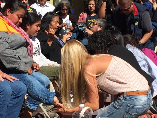 Una joven estadounidense lava los pies a inmigrantes centroamericanos en proceso de deportación.