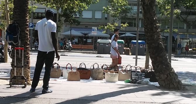 Un 'mantero' vende bolsos en el paseo Joan de Borbó.