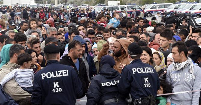 Agentes de policía dan instrucciones a los refugiados que esperan en la frontera con Hungría, 