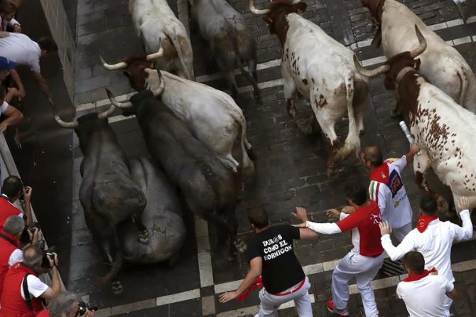 Los mozos corren en la curva de Mercaderes junto los toros de la ganadería abulense de José Escolar Gil, en el tercer encierro de los Sanfermines 2016, en el que uno de los astados se ha dado la vuelta unos segundos después de salir de los corrales con la manada y ha creado momentos de gran tensión.
