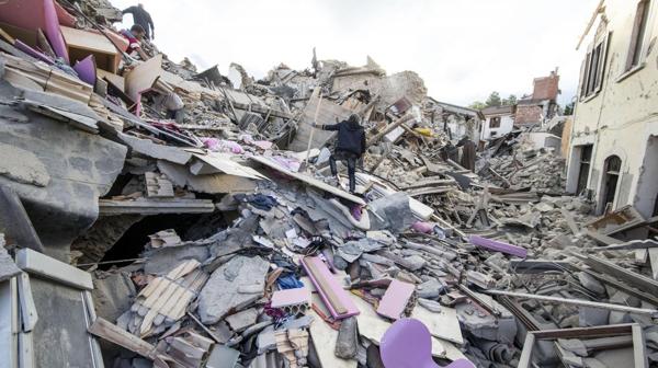 Un hombre camina sobre los restos de una casa en Amatrice