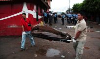 Personal forense traslada el cuerpo de uno de los ocho jóvenes asesinados en una tienda el 14 de agosto de 2016 en Tegucigalpa