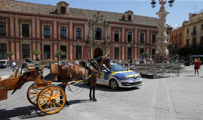 La Policía Local de Sevilla ha detenido a un hombre de unos 40 años después de apuñalar mortalmente a otro en pleno centro sevillano. En la fotografía, un coche de patrulla de la policía estacionado al lado de un coche de caballos en Sevilla.