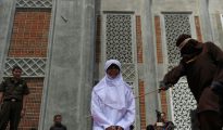 Un oficial religioso azota a una mujer castigada por tener una cita fuera del matrimonio, contraviniendo la ley islámica o sharia, el 1 de agosto de 2016 fuera de la mezquita de Banda Aceh, en Indonesia