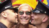 Dos gais vestidos de policías besan a un compañero durante el desfile del 'Christopher Street Day' en Berlín.