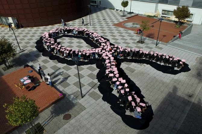 Estudiantes forman un lazo rosa durante un Día Mundial del Cáncer de Mama.