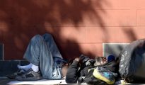Un hombre sin hogar duerme al lado de una pared en la acera a lo largo de una calle en el centro de Los Angeles, California, el 9 de febrero de 2016