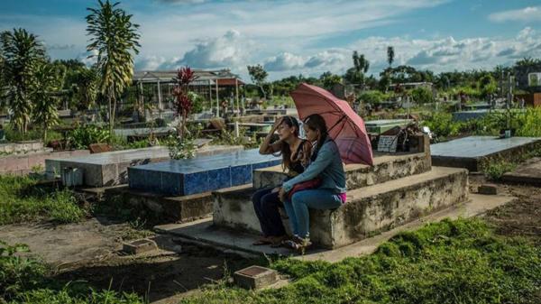 Yamilet Lugo (izquierda) llora frente la tumba de su hijo Kevin